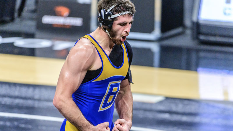 CSUB wrestler flexing muscles after a match