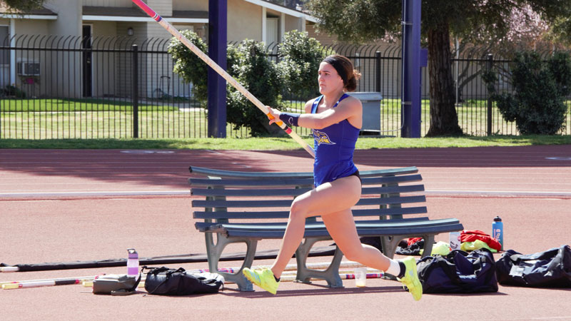 CSUB female pole vaulter holding the pole and running toward the obstacle