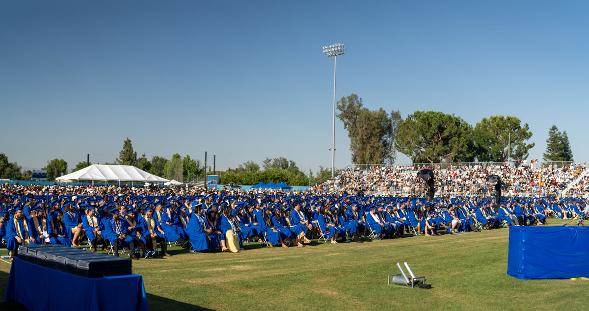Hundreds of CSUB graduates sitting outdoors at a commencement ceremony